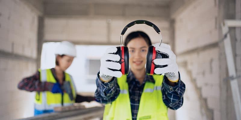 woman holding hearing protection on work site