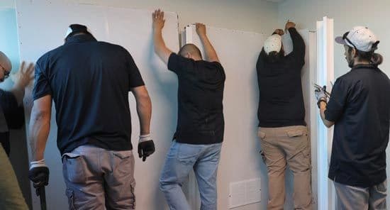 e3 Diagnostics booth installers holding a wall for sound booth